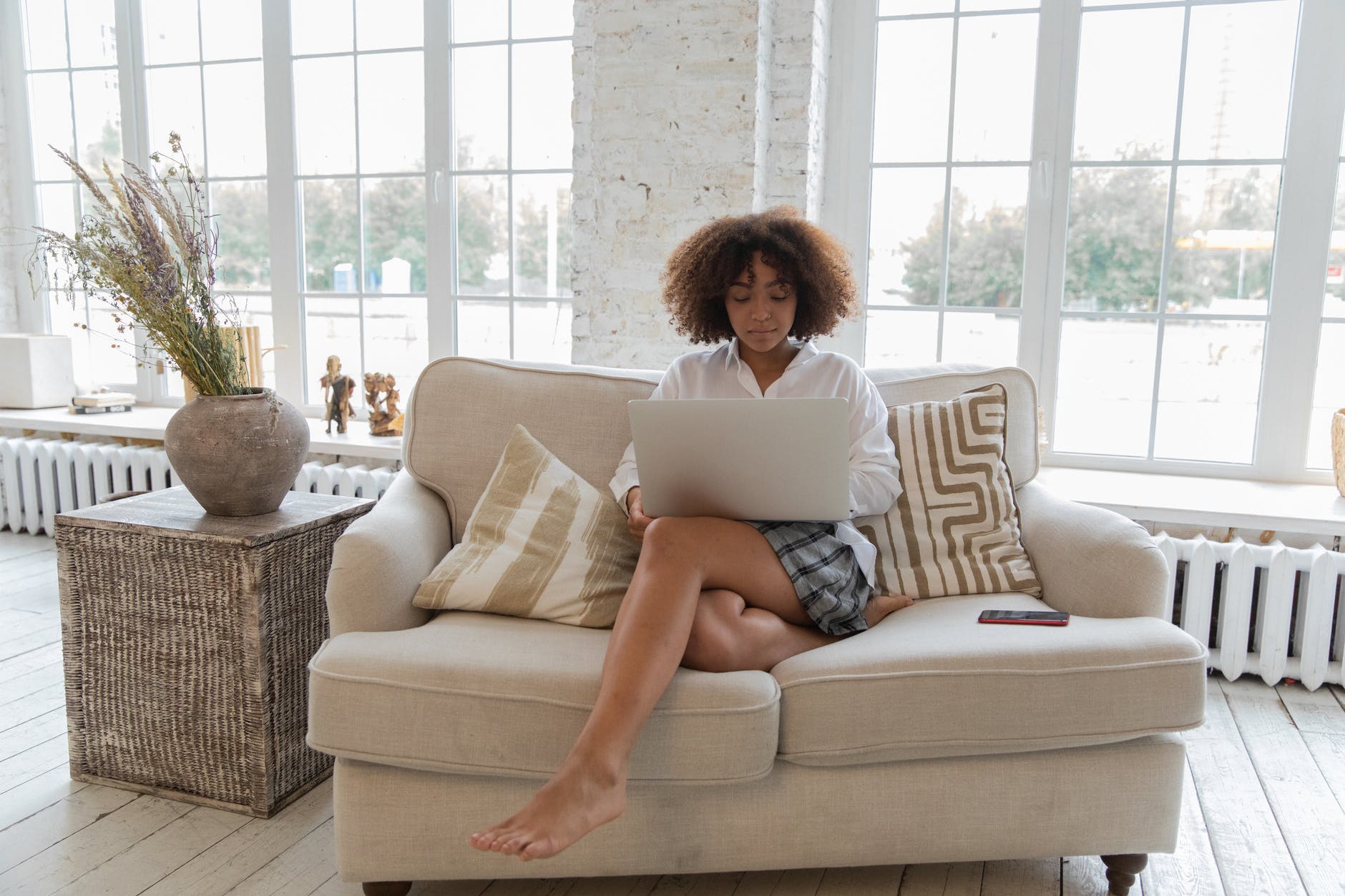 concentrated young black lady using laptop during remote work on couch