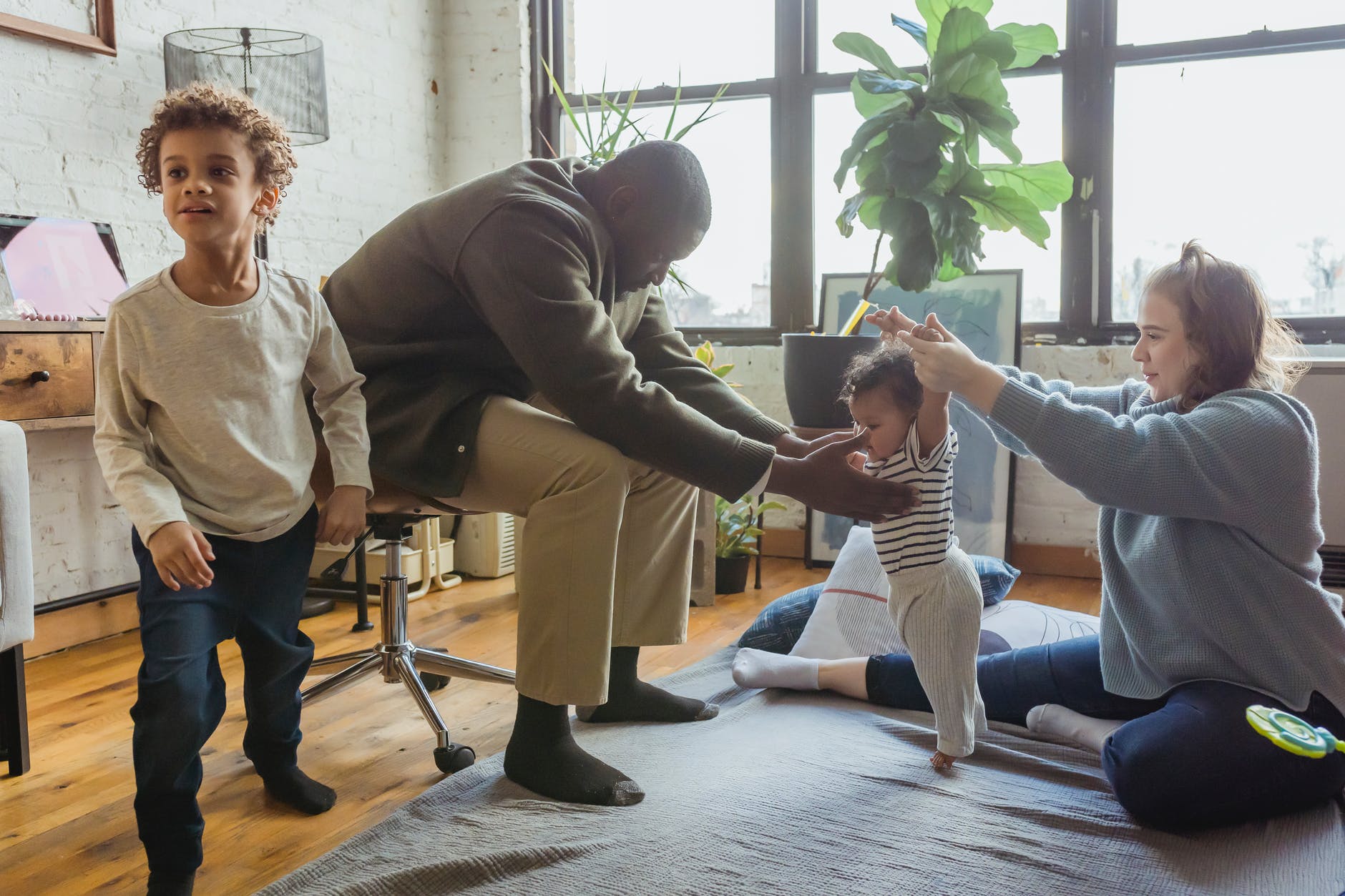 multiethnic family playing with children on blanket on floor